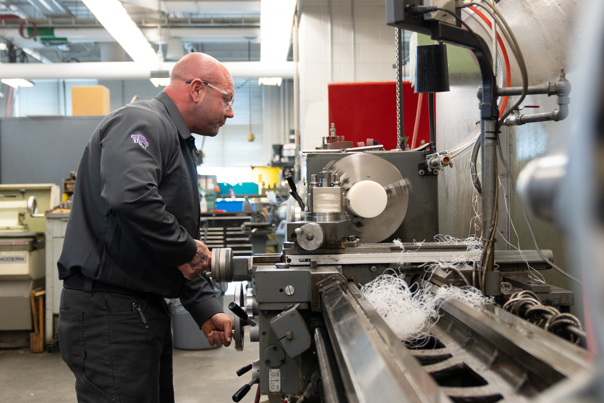 Technician using a lathe machine to shape a piece of metal